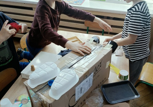 dzieci konstruują z pudełek i plastiku samochód