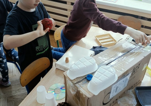 dzieci konstruują z pudełek i plastiku samochód
