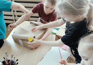 dzieci konstruują z pudełek i plastiku samochód