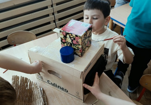 dzieci konstruują z pudełek i plastiku samochód