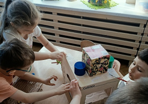 dzieci konstruują z pudełek i plastiku samochód