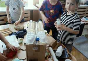 dzieci konstruują z pudełek i plastiku samochód