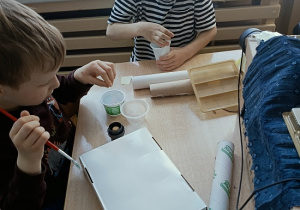 dzieci konstruują z pudełek i plastiku samochód