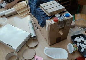 dzieci konstruują z pudełek i plastiku samochód