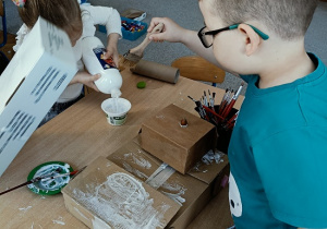 dzieci konstruują z pudełek i plastiku samochód