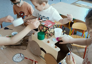 dzieci konstruują z pudełek i plastiku samochód