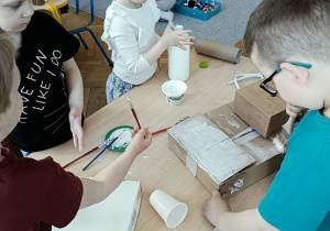 dzieci konstruują z pudełek i plastiku samochód