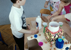 dzieci konstruują z pudełek i plastiku samochód