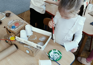 dzieci konstruują z pudełek i plastiku samochód