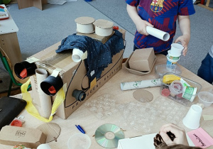 dzieci konstruują z pudełek i plastiku samochód