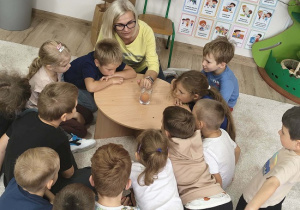 dzieci słuchają nauczycielki, która tłumaczy doświadczenie