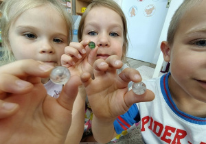 dziewczynki i chłopiec pokazują kolorowe kulki
