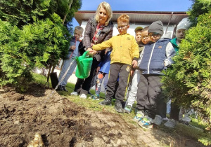 chłopiec podlewa konewką zasadzone cebulki