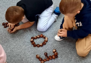 Dzieci układają kształty z kasztanów