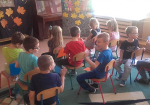 dzieci siedzą na krzesłach w zabawie ,,Autobus z figurami geometrycznymi''