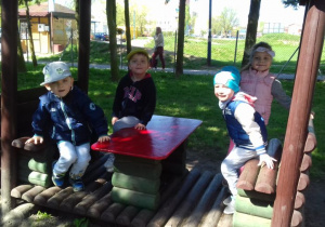 dzieci siedzą w drewnianej lokomotywie