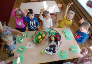Dzieci pokazują jabłko.