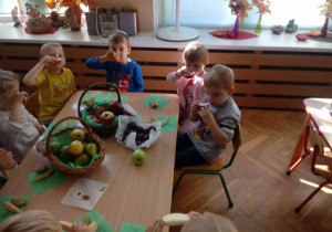 Dzieci wąchają owoc.