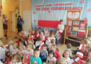 dzieci siedza w gromadce w strojach biało- czerwonych