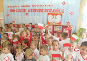 dzieci w strojach biało- czerwonych machają flagami