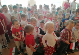 dzieci w strojach biało- czerwonych na stojąco śpiewają hymn