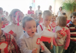 dzieci ubrane na biało- czerwono machają chorągiewkami