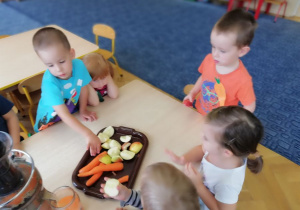 dzieci wrzucaja warzywa i owoce do sokownika