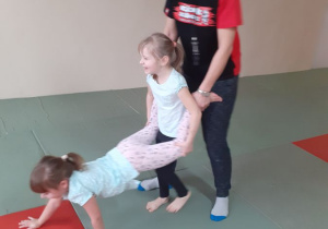 Trenerka pomaga dzieciom w ćwiczeniu