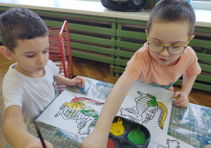 Mikołaj i Bartuś malują farbami smoka