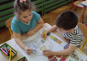 Oliwia i Kacper kolorują plakat Kotka Zdrowotka
